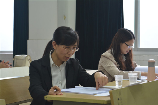 图四:答辩组老师认真审阅员工的论文材料.jpg